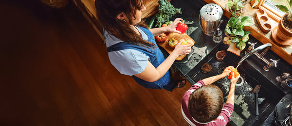 A mother and her son stand in the kitchen washing veggies with clean, filtered tap water.