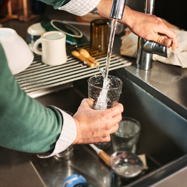 A man fills a glass with water. 